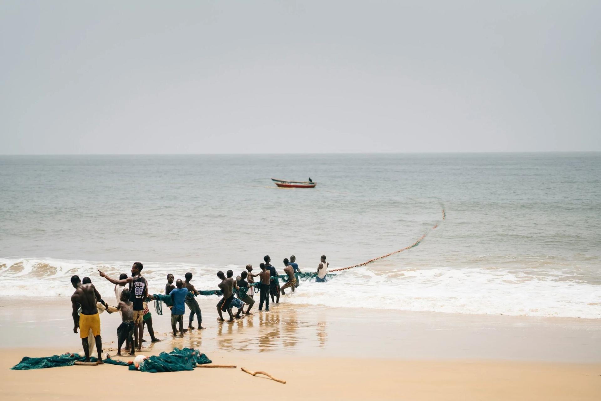 Fishermen hauling nets on a West African beach